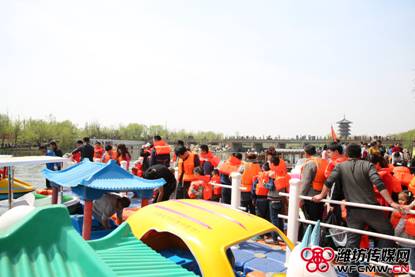 清明假期湿地公园内，游客们穿着橙色救生衣排着长队等待游玩新增的水上项目